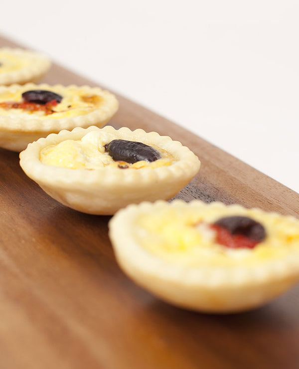 A photo of Mini quiche with Meredith goats cheese, roasted capsicum and topped with kalamata olives.