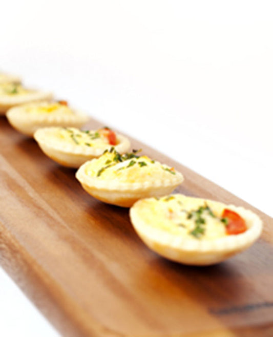 A photo of Mini egg and bacon quiche topped with cherry tomatoes and chives. 