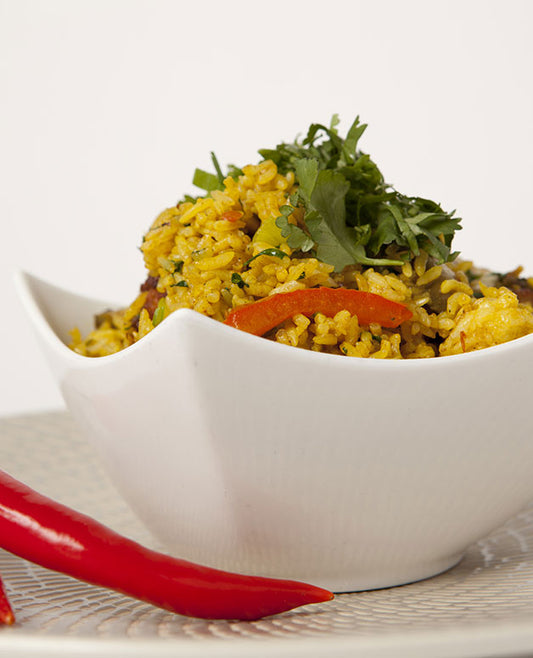 A photo of a Malaysian style fried rice with chicken, mushrooms, red capsicum, mild chilli, turmeric and garlic. 